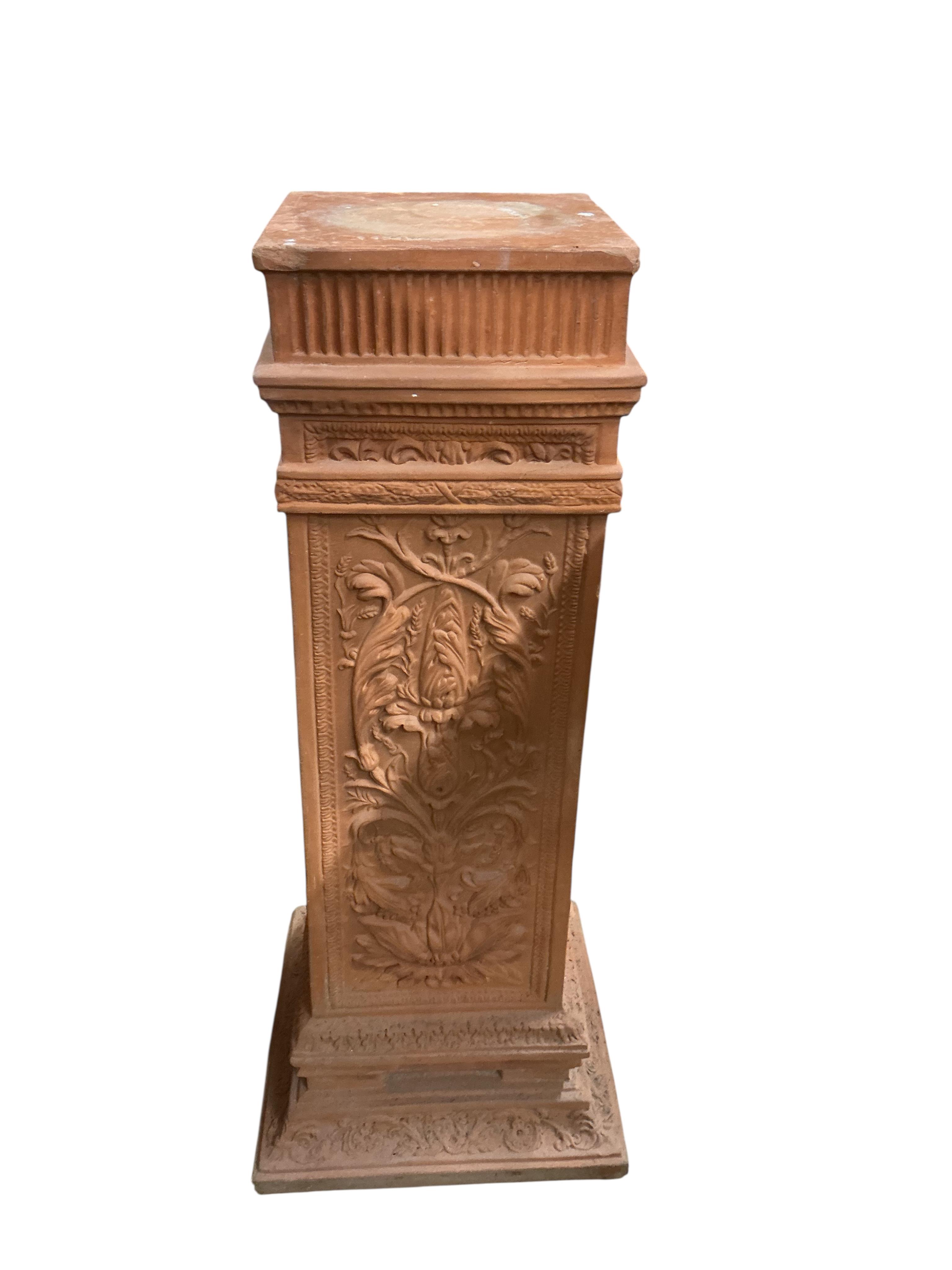 A pair of terracotta pedestals, decorated with panels of scrolling foliage, width 45cm, height 109cm